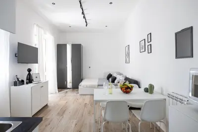 a white kitchen and living room with a table and chairs at Uditore Mini Apartment in Palermo