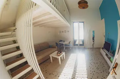 a living room with a couch and a staircase at Casa TreMar - Flat with roof top in Mondello in Palermo