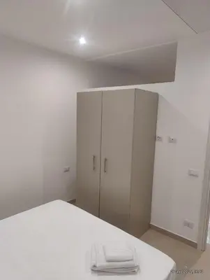 a white bedroom with a bed and a cabinet at Le casette di Elia e Alice in Palermo