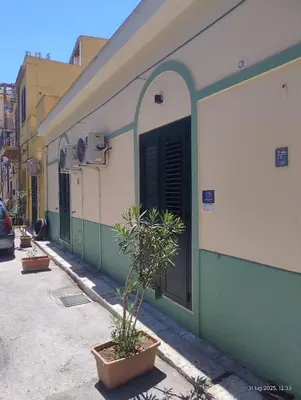 a green and white building with a door and plants at Le casette di Elia e Alice in Palermo
