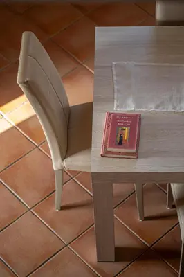 a chair sitting next to a table with a book at Villa Luna Scopello in Castellammare del Golfo