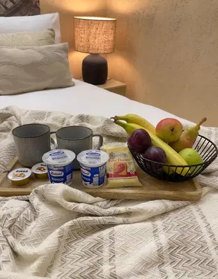 a tray of fruit and yogurt on a bed at Bìfara Rooms in Palermo