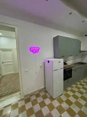 a kitchen with a white refrigerator and a purple sign on the wall at Don Bosco Suite in Palermo