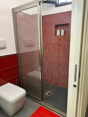 a bathroom with a shower with a toilet and red tiles at Matteotti 17 Easy in Cinisi