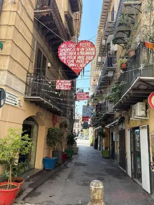 an alley with two hearts hanging from the buildings at That's Amuri in Palermo