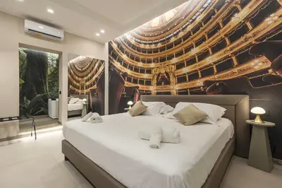 a bedroom with a large white bed with a mural on the wall at Lolli Boutique & SPA Al Massimo in Palermo