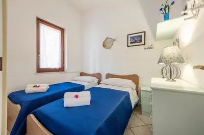 two beds in a small room with blue sheets at Acquamarina 24 in San Vito lo Capo