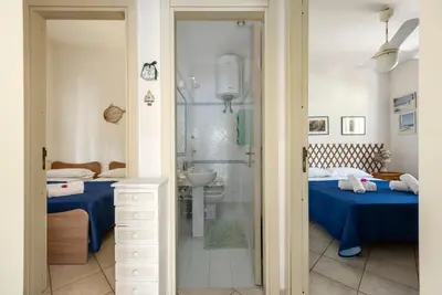 a bedroom with two beds and a shower and a bathroom at Acquamarina 24 in San Vito lo Capo