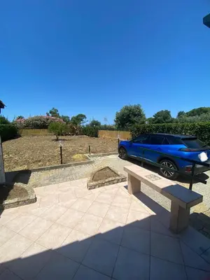 a blue car parked in a parking lot with a bench at Villa Maria in Campofelice di Roccella