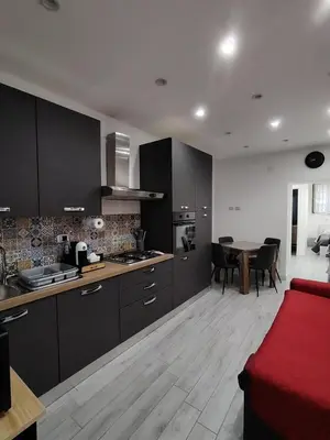 a living room with a red couch and a kitchen at La Casetta di Nonno Settimo in Palermo