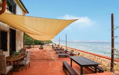 a patio with tables and chairs and the ocean at Nice Apartment In Trappeto With Wifi in Trappeto