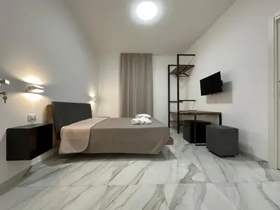 a bedroom with a bed and a desk and a television at BreMi Rooms B&B in San Vito lo Capo