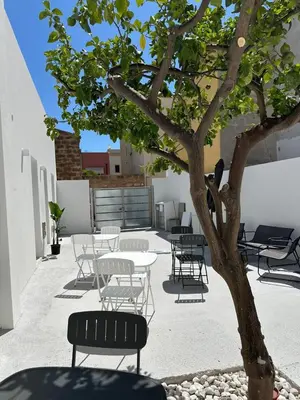 a patio with tables and chairs next to a tree at BreMi Rooms B&B in San Vito lo Capo