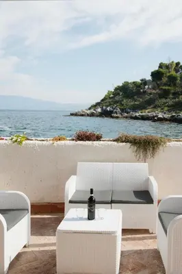 a patio with white chairs and a table and the ocean at Casetta Bianca Luxury in Santa Flavia