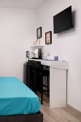 a room with a kitchen with a desk and a tv at Matrice Rooms in Palermo