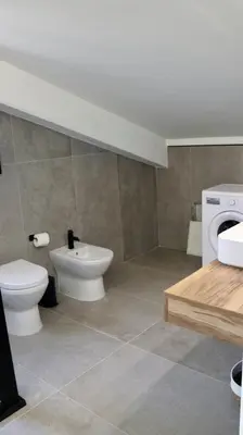 a bathroom with a toilet and a washing machine at Villa Zagara modern villa with pool in Lascari