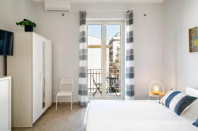 a white bedroom with a bed and a balcony at Casa del Saraceno in Palermo