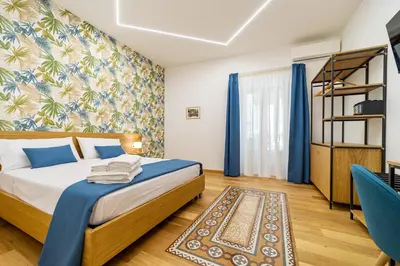 a bedroom with a bed and blue curtains and a chair at Bed & Theatre - Palermo in Palermo
