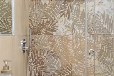 a shower with a glass door with a tropical wallpaper at Casa Florio Love Palermo in Palermo