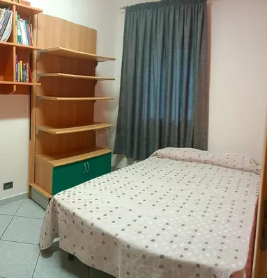 a bedroom with a bed and a book shelf at Appartamento vista mare in Castellammare del Golfo