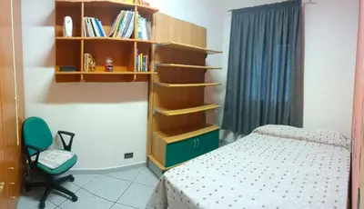 a bedroom with a bed and a book shelf at Appartamento vista mare in Castellammare del Golfo