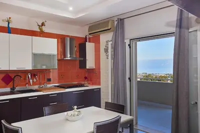 a kitchen with a table and a view of a balcony at Appartamento vista mare in Castellammare del Golfo