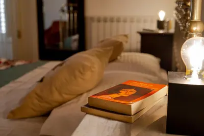 two books sitting on top of a bed with a lamp at Artista Apartment in Alcamo