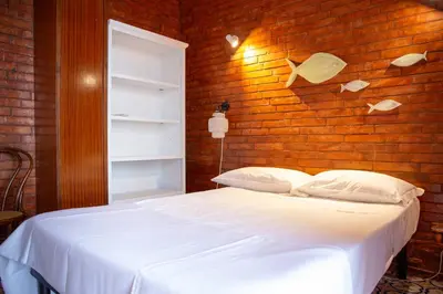 a bedroom with a white bed and a brick wall at Solemar Sicilia - Villa Giovitto in Bagheria