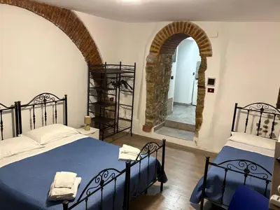 a bedroom with two beds and an arched doorway at Cortili Himeresi in Termini Imerese