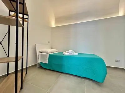 a small room with a bed with a blue blanket at Leonetti Due in Carini