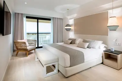 a bedroom with a large white bed and a chair at Grand Palladium Sicilia Resort & Spa in Campofelice di Roccella