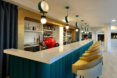 a bar with a blue and white counter and chairs at Grand Palladium Sicilia Resort & Spa in Campofelice di Roccella
