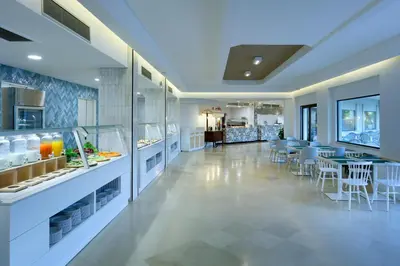 a large kitchen with a dining area with tables and chairs at Grand Palladium Sicilia Resort & Spa in Campofelice di Roccella