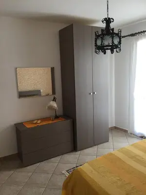 a bedroom with a bed and a cabinet and a chandelier at Dall'Orso Grigio in Balestrate