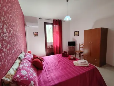 a bedroom with a pink bed with a pink blanket at ClimaDerna SX Climatizzata in Castellammare del Golfo