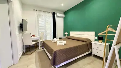 a bedroom with a green wall and a bed and a desk at Rooms, eleganza moderna nel centro storico di Palermo in Palermo