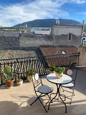 a patio with two chairs and a table on a roof at Casetta in piazza in Palazzo Adriano