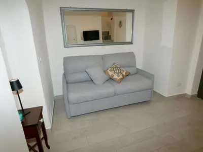 a gray couch in a living room with a mirror at Casetta al Duomo in Monreale