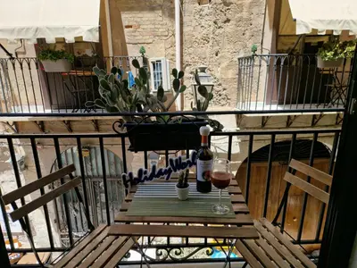 a table with wine bottles and glasses on a balcony at Il Fico d'India by Holiday World in Palermo