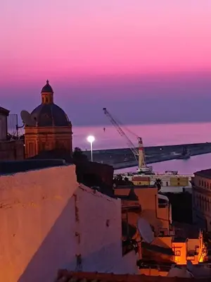 a sunset over a city with a building and a crane at Holiday House Annunziata in Termini Imerese