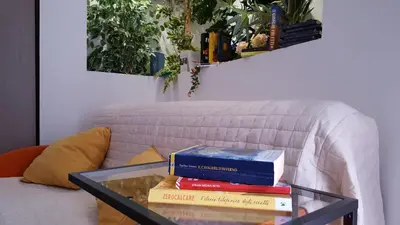 a stack of books on a glass table next to a couch at Oasi del Libro in Castellammare del Golfo