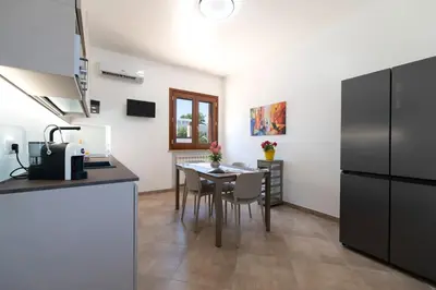 a kitchen with a table with chairs and a refrigerator at Villa Giunella in San Vito lo Capo