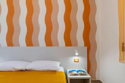 a bedroom with a yellow bed with a striped wall at Villa Giunella in San Vito lo Capo