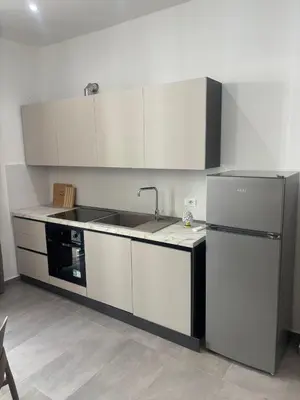 a kitchen with white cabinets and a sink and a refrigerator at A due passi in Balestrate