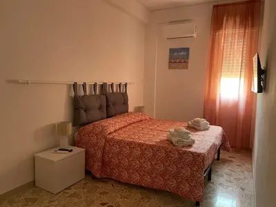 a bedroom with a bed with a red bedspread at Il Sole di Palermo in Palermo