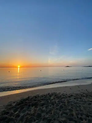 a beach with the sun setting over the water at Cinque Raggi di Sole in Isola delle Femmine