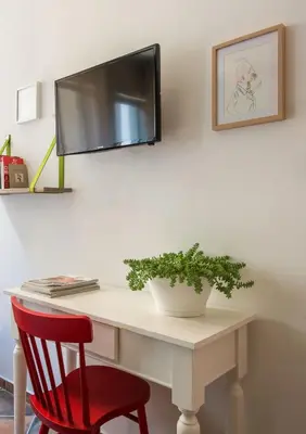 a desk with a red chair and a tv on a wall at Cassaro261 in Palermo