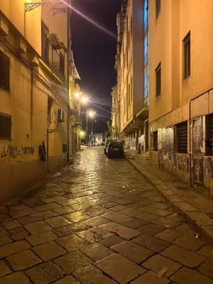 an empty street at night with a car driving down it at Casa Marì-Albergheria in Palermo's historic center in Palermo