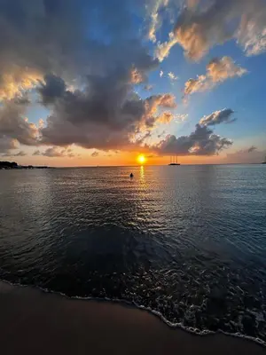 a sunset over the ocean with a boat in the water at La casetta di Totò in Palermo
