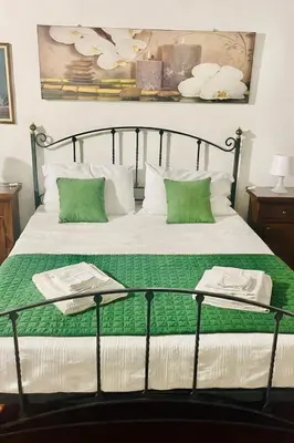 a bed with green and white sheets and pillows at La Suite nel Centro di Palermo in Palermo